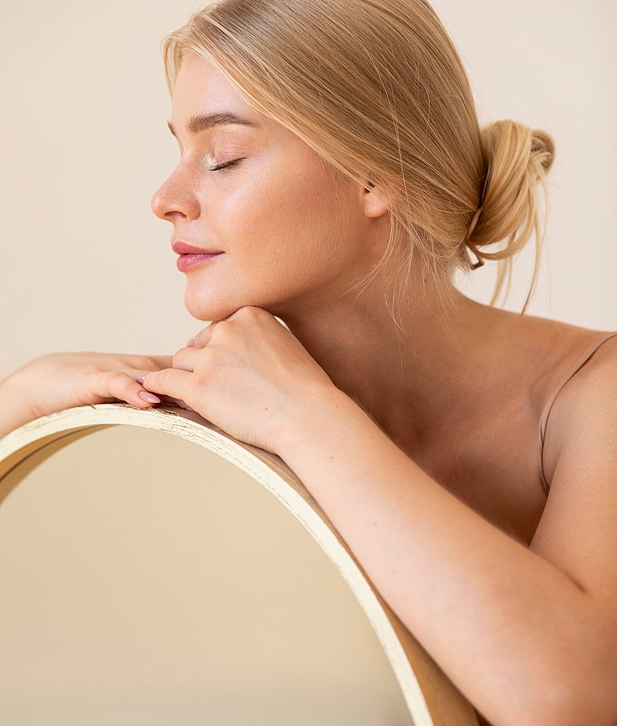 Woman relaxing by a round mirror, eyes closed.