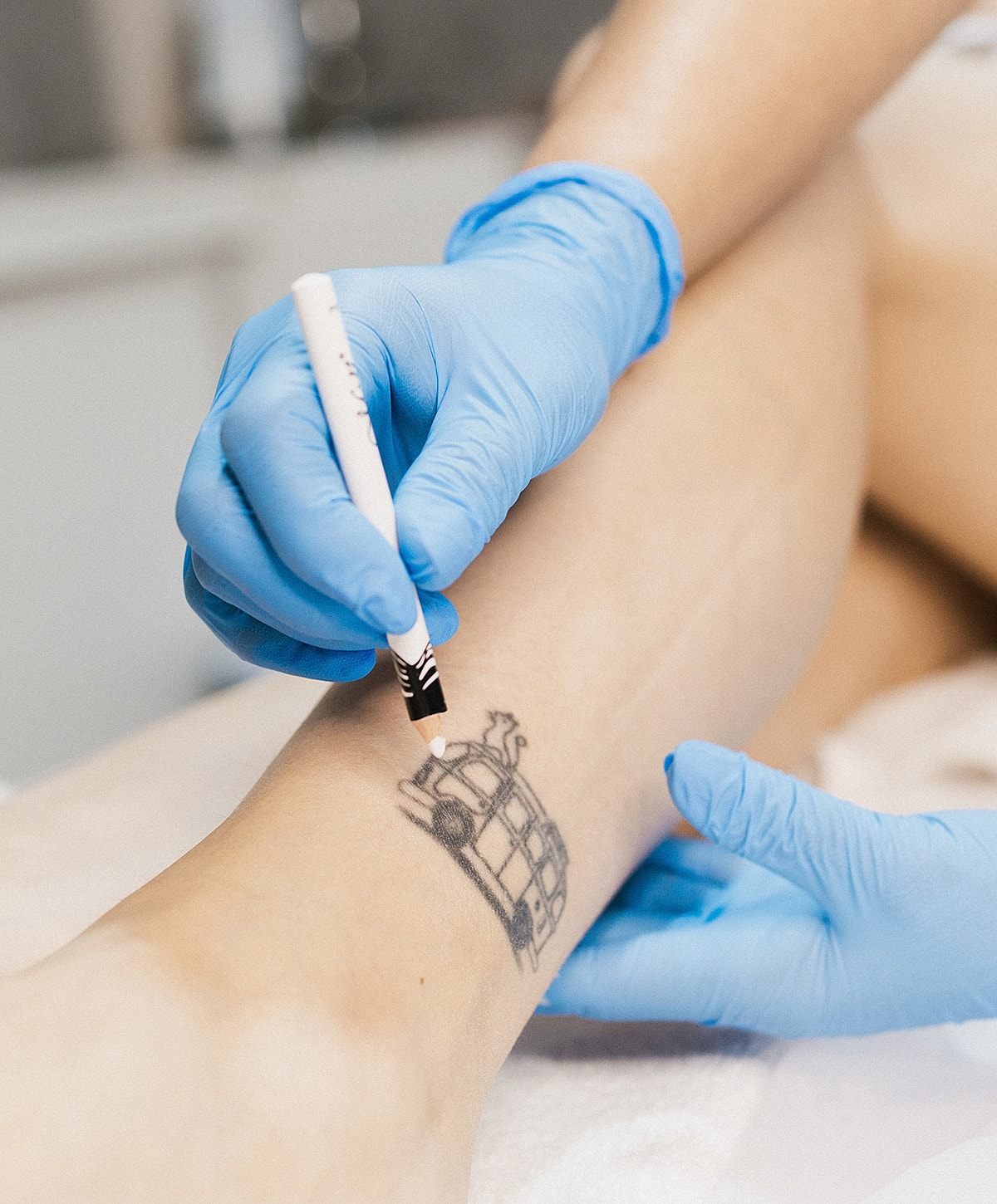 Tattoo artist marking design on client's leg.