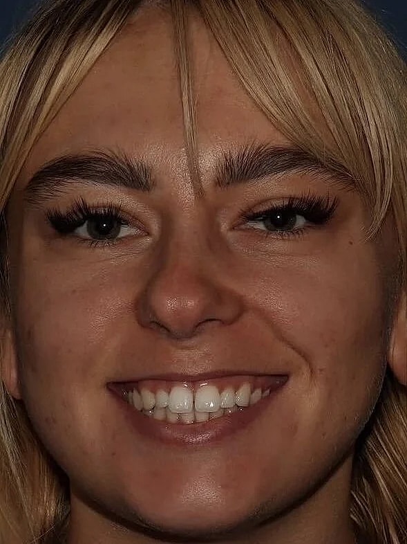 Smiling person with blonde hair and makeup.