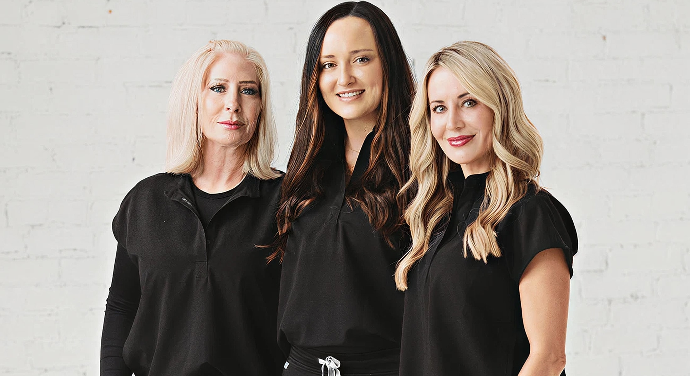 Three smiling women in black shirts.
